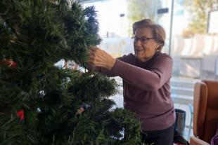 Persona mayor decorando el árbol de navidad